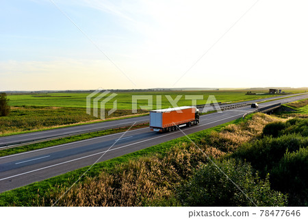Truck with semi-trailer driving along highway on the sunset background.  78477646