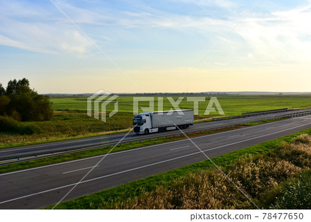 Truck with semi-trailer driving along highway on the blye sky and sunset background.  78477650