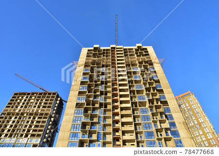 Tower cranes working at construction site on blue sky background. Tower cranes working at construction site on blue sky background. 78477668