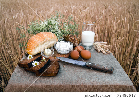 Organic food - milk, bread, eggs, cheese, butter, knife, lying on the table, against the background 78480618