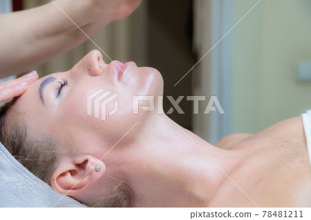The girl is given a face and neck massage in a beauty salon. 78481211