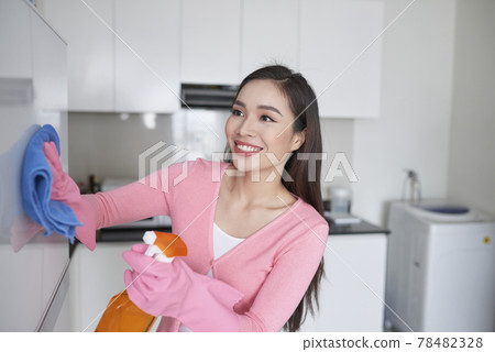 Woman in protective gloves cleaning refrigerator with rag indoors Woman in protective gloves cleaning refrigerator with rag indoors 78482328
