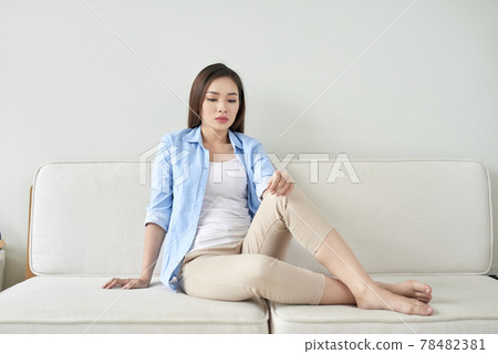 Depressed young woman sitting on sofa at home Depressed young woman sitting on sofa at home 78482381