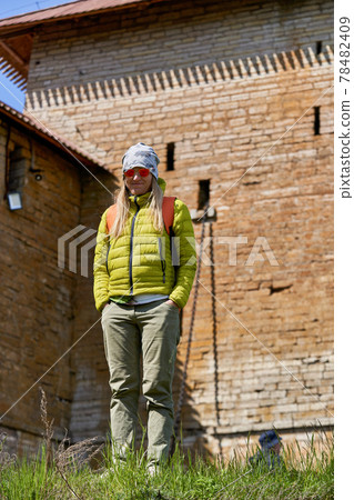 girl stands against background of an old brick fortress wall with a watchtower 78482409