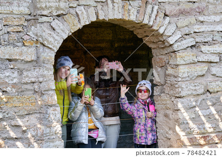 A family of tourists takes pictures of the landmark on a mobile phone A family of tourists takes pictures of the landmark on a mobile phone 78482421