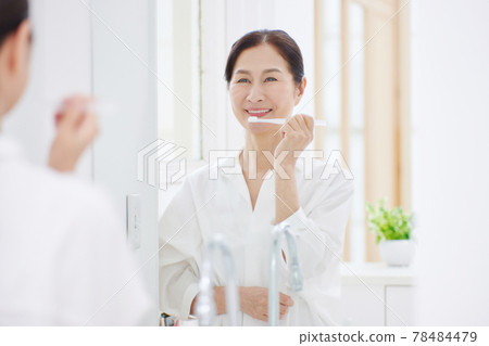Senior woman with a toothbrush in the living room Senior woman with a toothbrush in the living room 78484479