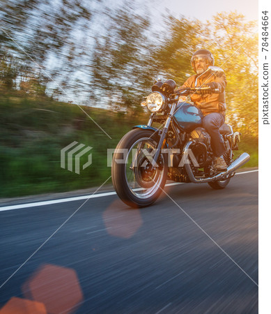 Motorcycle driver riding in Alpine landscape. 78484664