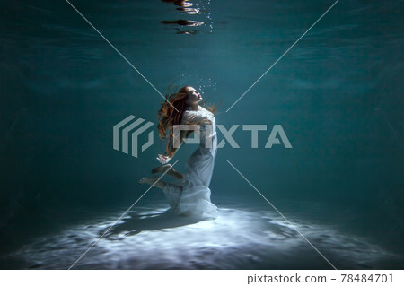 Woman in a dress is dancing underwater. Woman in a dress is dancing underwater. 78484701