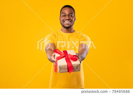 Black Guy Giving Wrapped Present Box To Camera, Yellow Background 78485686