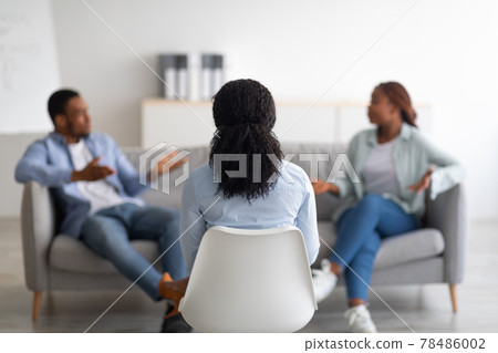 Marital therapy. Psychologist sitting with her back to camera during appointment with unhappy black couple at office Marital therapy. Psychologist sitting with her back to camera during appointment with unhappy black couple at office 78486002