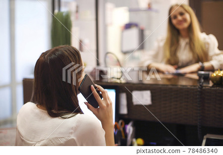 Woman writing appointment of client in salon 78486340