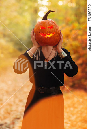 Young witch with jack o lantern in forest Young witch with jack o lantern in forest 78486350