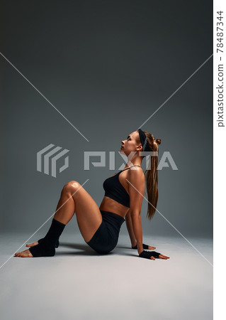 Beautiful advance yogi showing her incredible flexibility with an animal flow move in studio against a gray background 78487344