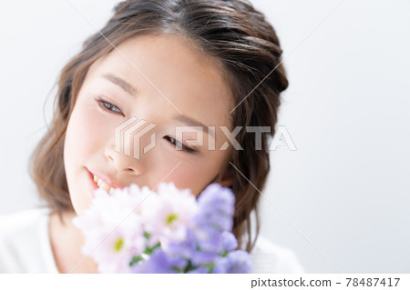 Portrait of a young woman smiling with a bouquet on a white background 78487417
