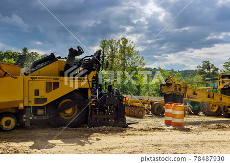 Under construction of a new asphalt road. The excavators, graders working on the new road construction Under construction of a new asphalt road. The excavators, graders working on the new road construction 78487930