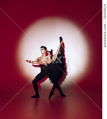 Ballet dancers dancing over red studio background. Modern design. Contemporary colorful conceptual light as rising sun at Japan. Ballet dancers dancing over red studio background. Modern design. Contemporary colorful conceptual light as rising sun at Japan. 78488024