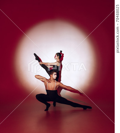 Ballet dancers dancing over red studio background. Modern design. Contemporary colorful conceptual light as rising sun at Japan. Ballet dancers dancing over red studio background. Modern design. Contemporary colorful conceptual light as rising sun at Japan. 78488025