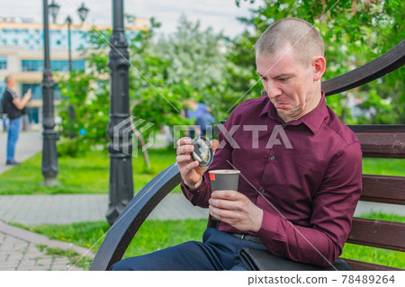 Office worker on a park bench opened a glass of coffee 78489264