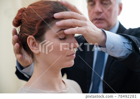 Mature gray-haired man hypnotizes Caucasian woman during hypnotherapy session. The psychologist uses alternative treatments for the subconscious mind Mature gray-haired man hypnotizes Caucasian woman during hypnotherapy session. The psychologist uses alternative treatments for the subconscious mind 78492281
