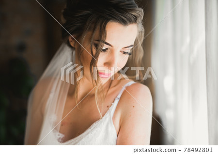 Gorgeous bride in robe posing and preparing for the wedding ceremony face in a room Gorgeous bride in robe posing and preparing for the wedding ceremony face in a room 78492801