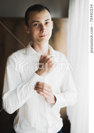 Grooms morning preparation. Handsome man getting dressed and preparing for the wedding Grooms morning preparation. Handsome man getting dressed and preparing for the wedding 78492834