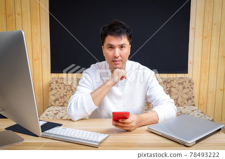 asian handsome man using smartphone and smiling while working from home asian handsome man using smartphone and smiling while working from home 78493222