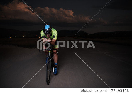 triathlon athlete riding bike fast at night 78493538