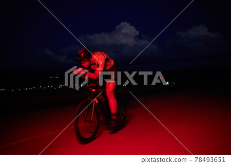 triathlon athlete riding bike fast at night 78493651