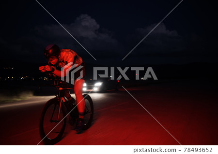 triathlon athlete riding bike fast at night 78493652