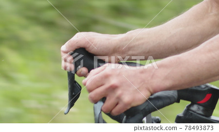 Closeup of the curved steering wheel of a road bike, the hands of a cyclist switching speed while driving on the road. Closeup of the curved steering wheel of a road bike, the hands of a cyclist switching speed while driving on the road. 78493873
