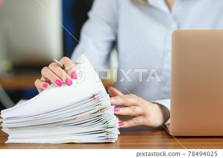 Woman holding many documents with multicolored paper clips in her hands in office closeup Woman holding many documents with multicolored paper clips in her hands in office closeup 78494025