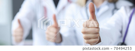 Three doctors stand behind each other and hold their thumbs up 78494253