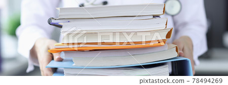 Doctor is holding large stack of folders 78494269