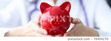 Doctor holds piggy bank in his hands 78494270