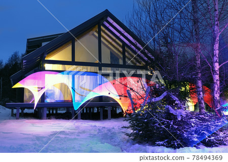 Winter modern house illuminated with abstract magic LED lights in blue winter evening Winter modern house illuminated with abstract magic LED lights in blue winter evening 78494369