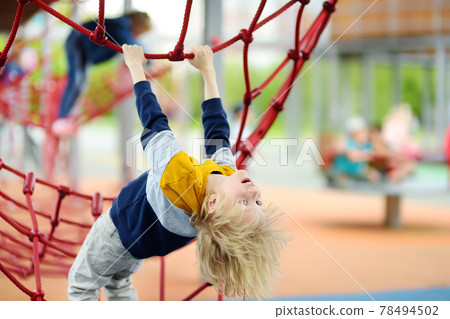 Perky preschooler boy having fun on outdoor playground. Spring/summer/autumn active sport leisure for kids. Outdoor activities for children. 78494502