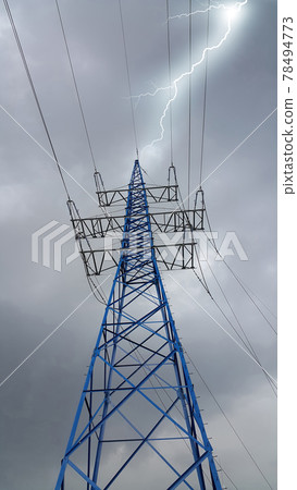 High voltage tower against the cloudy sky with lightning strike 78494773