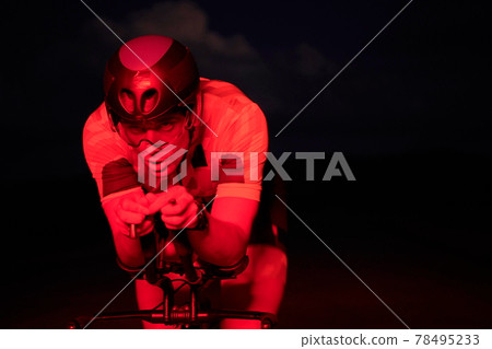 triathlon athlete riding bike fast at night 78495233