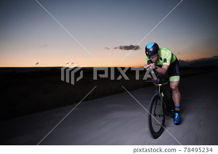 triathlon athlete riding bike fast at night 78495234