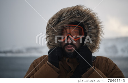 man at winter in stormy weather wearing warm fur jacket man at winter in stormy weather wearing warm fur jacket 78495343