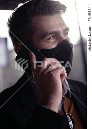 business man wearing coronavirus medical face mask while using smartphone business man wearing coronavirus medical face mask while using smartphone 78495344