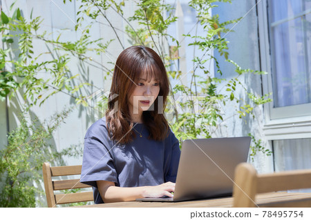 A woman working on a PC at a table on the terrace A woman working on a PC at a table on the terrace 78495754