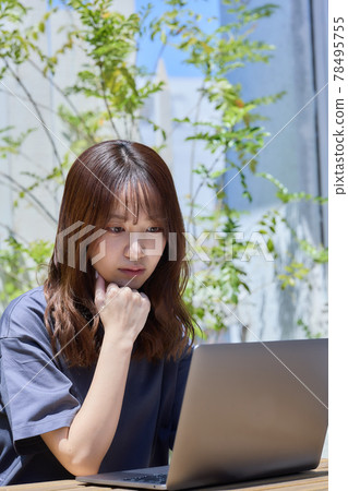 A woman working on a PC at a table on the terrace A woman working on a PC at a table on the terrace 78495755
