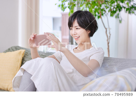 觀看在沙發的一位小姐一個智能手機 觀看在沙發的一位小姐一個智能手機 78495989