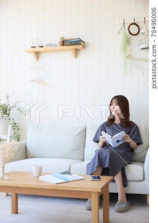 Woman looking at a book in the living room 78496006