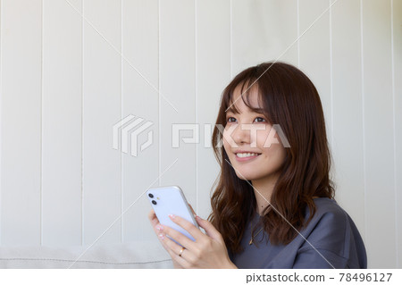 A woman looking at her smartphone in the living room 78496127