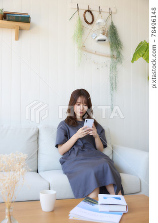 一個女人在客廳裡看著她的智能手機 一個女人在客廳裡看著她的智能手機 78496148