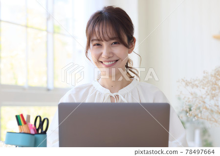 A woman using a computer at her desk 78497664