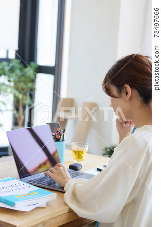 A woman using a computer at her desk 78497666