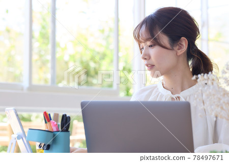 A woman using a computer at her desk 78497671
